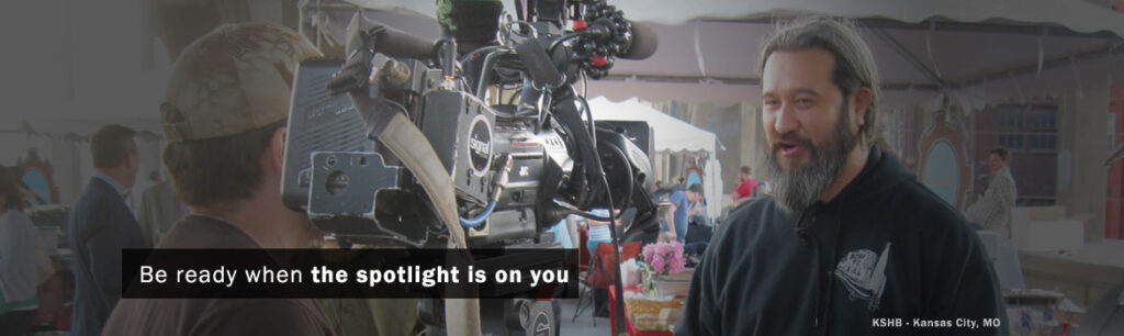 A man with a beard speaks to a camera operator at an outdoor event, emphasizing preparation for media attention.
